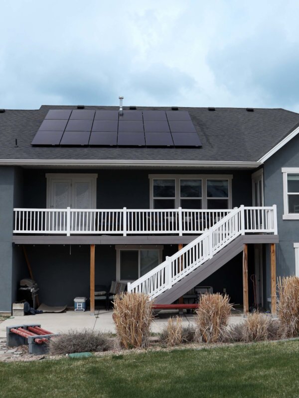 Back preview of two-story, grey-blue house with large solar panel system installed on roof