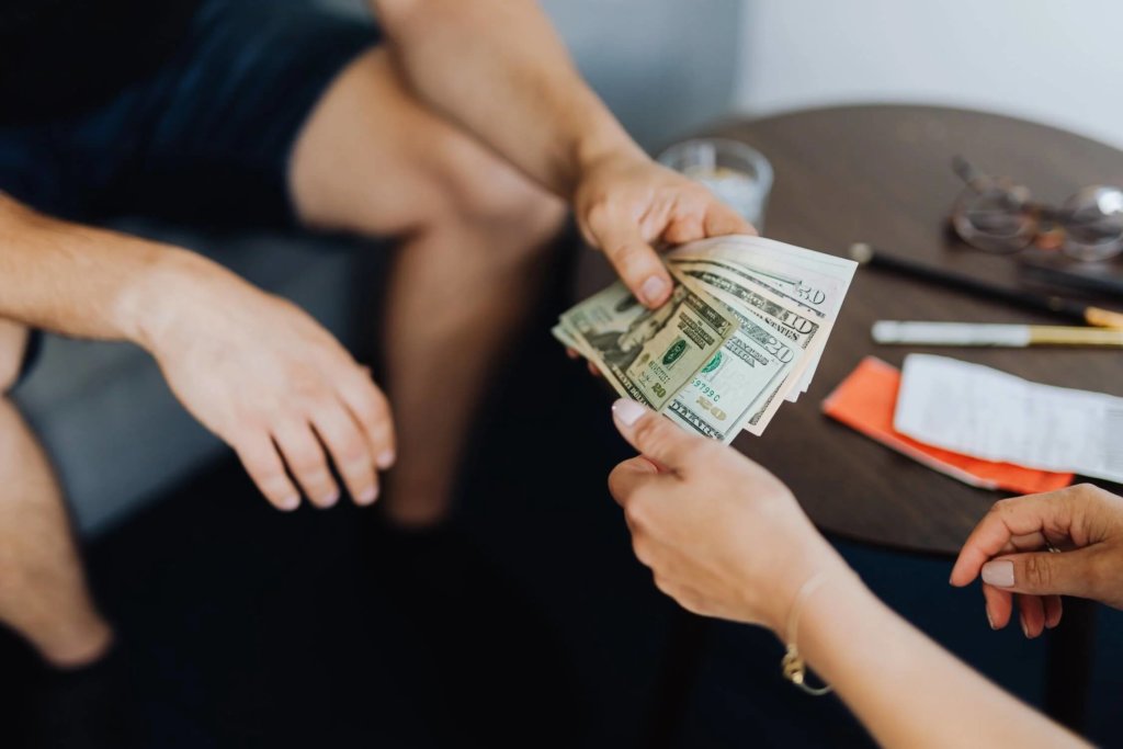 A fan of US dollar bills being exchanged between two individuals
