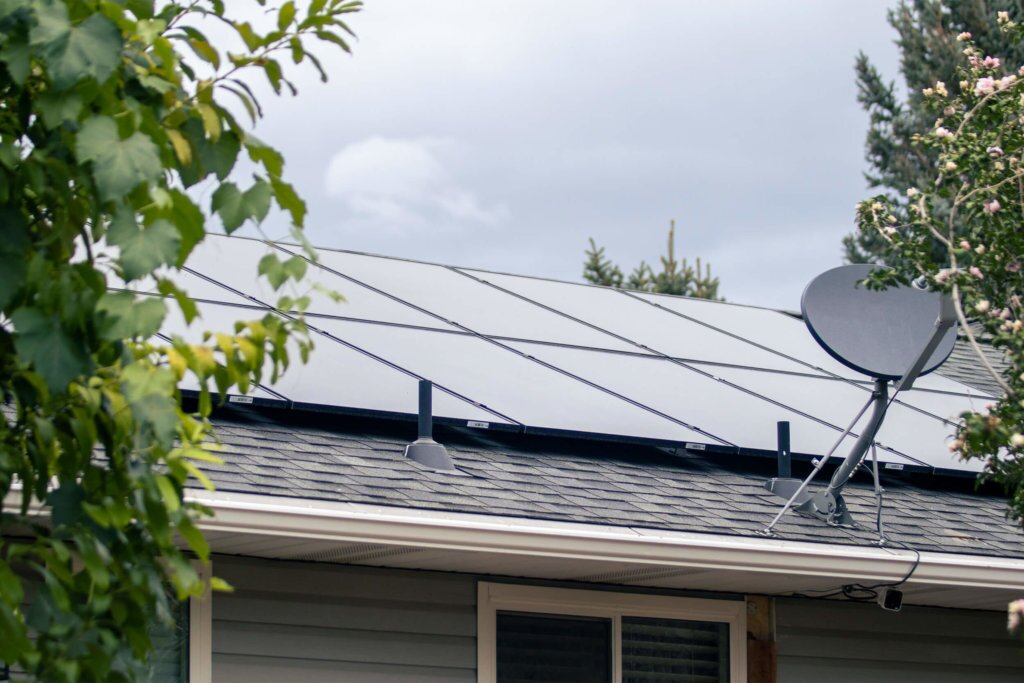Blue Raven Solar installation with large array of solar panels on roof and satellite dish, surrounded by trees