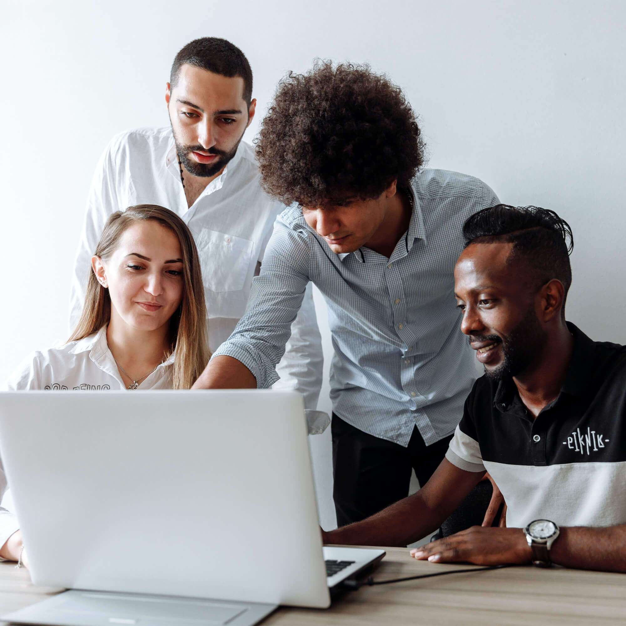 Three males and one female, gathered around a laptop - working in a group setting