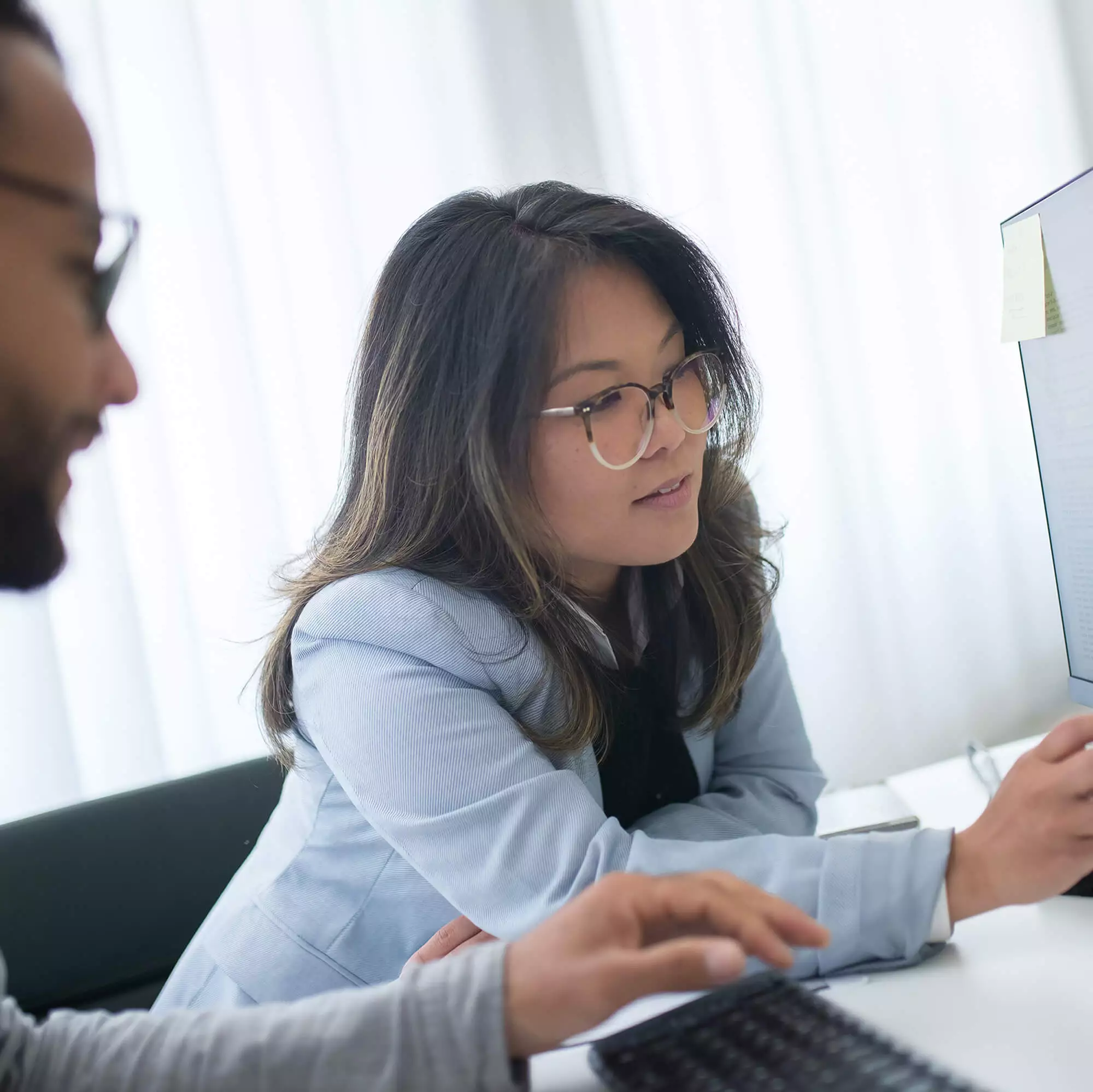 One male and one female, coworkers, evaluating data on a computer monitor