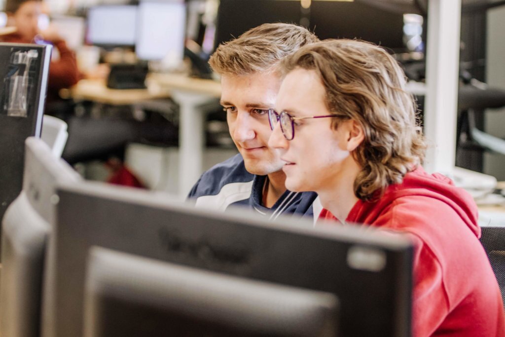 Two, male Blue Raven Solar employees working together on a computer monitor