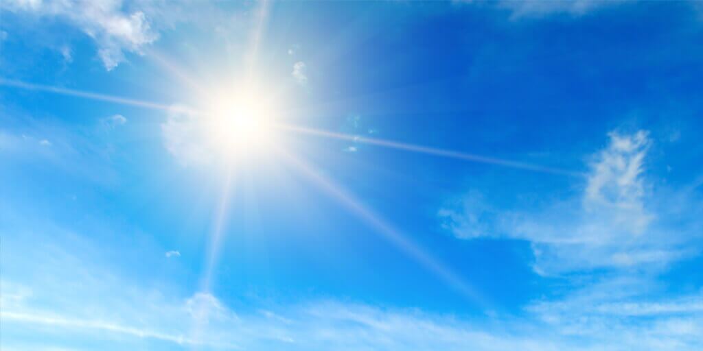 Sun flare in a blue sky, surrounded by wispy clouds