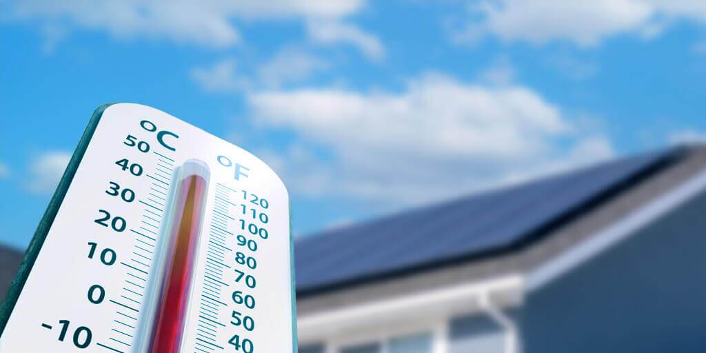 Large thermometer with a custom, PV solar panel system installed on a roof in the background