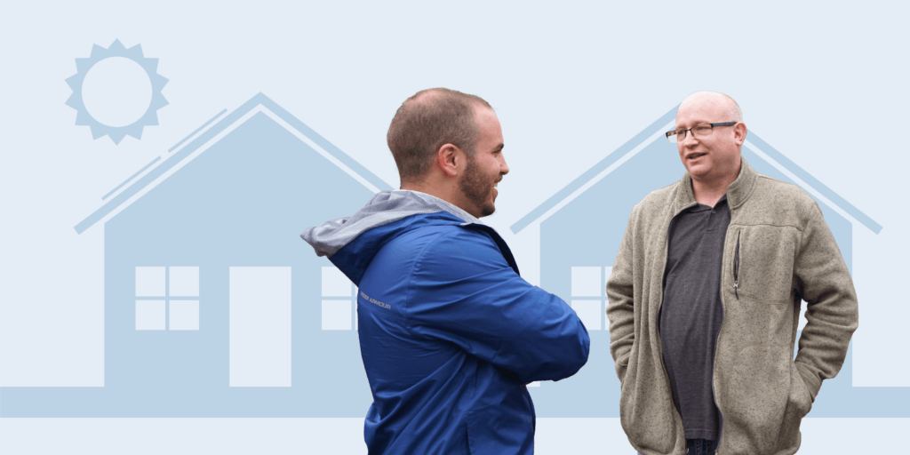 Finding a Reputable Solar Company-04 Two males standing and talking in front of two house graphics