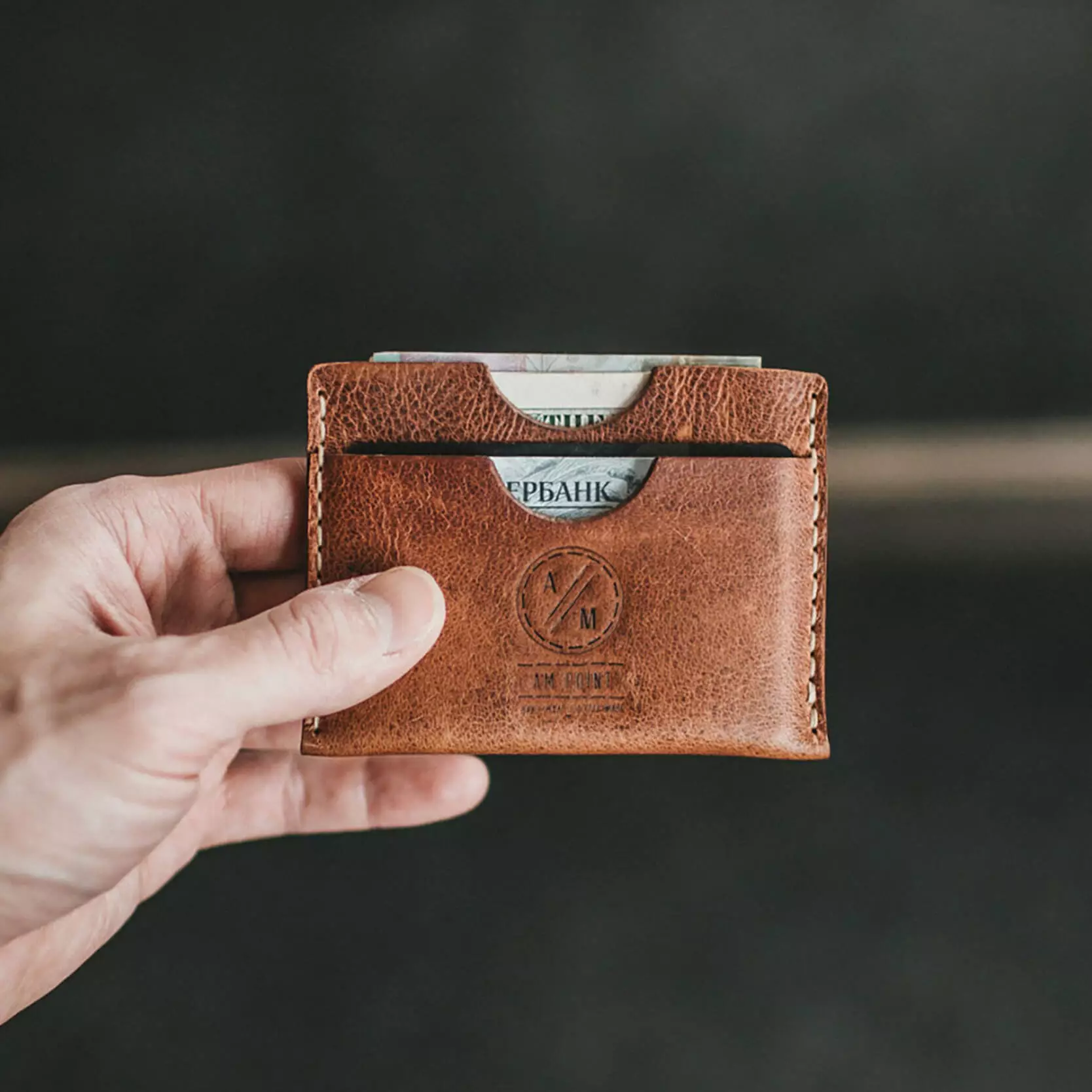 Male holding a brown leather wallet with cash and ID