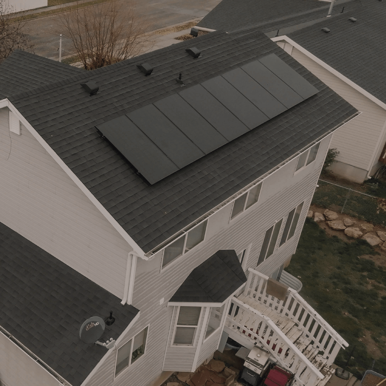 Aerial shot of a large two-story house with solar panels installed on different pitches