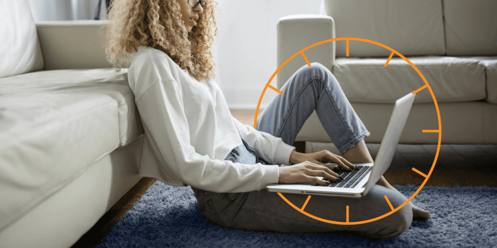 Young female, sitting on the floor, resting against a neutral colored couch and working on a laptop with an incomplete thin-line, orange icon similar to a clock