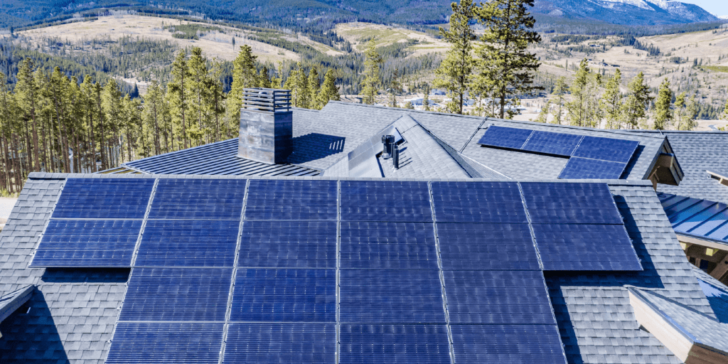 A 10-panel photovoltaic (PV) solar system installed on a large home with a mountain landscape and large green trees in the background