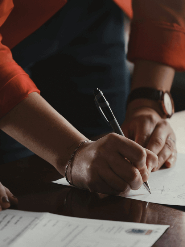 Two individuals signing documentation with a pen