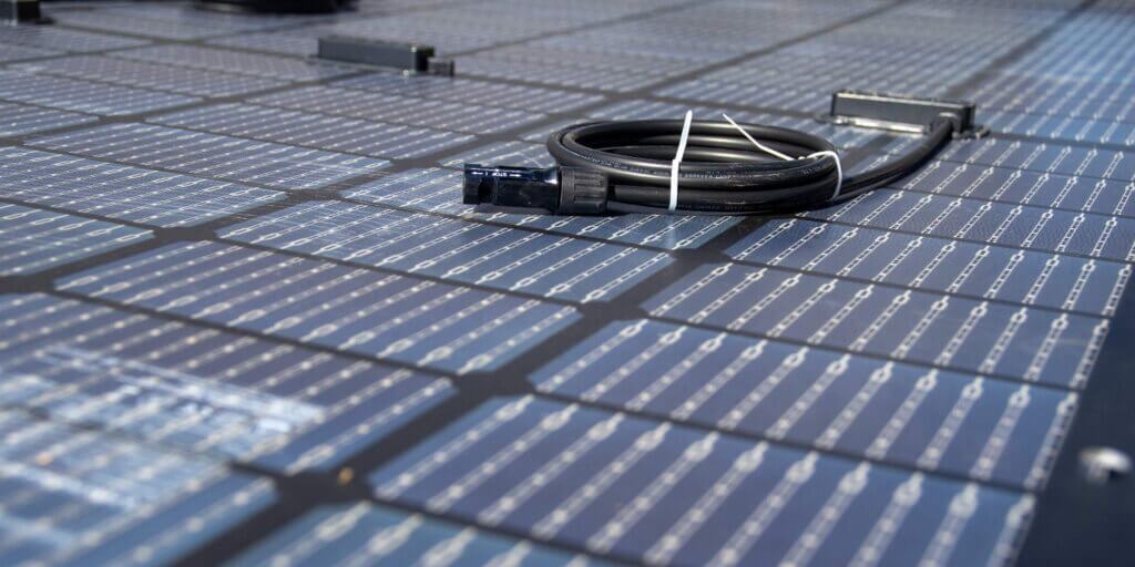 Up close of rooftop solar panel cells with the corresponding wiring coiled up