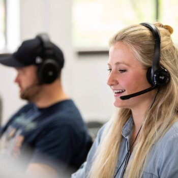 Blue Raven Staged Photos -4 Female Blue Raven Solar support representative with headset, talking on the phone with a customer and a male colleague next