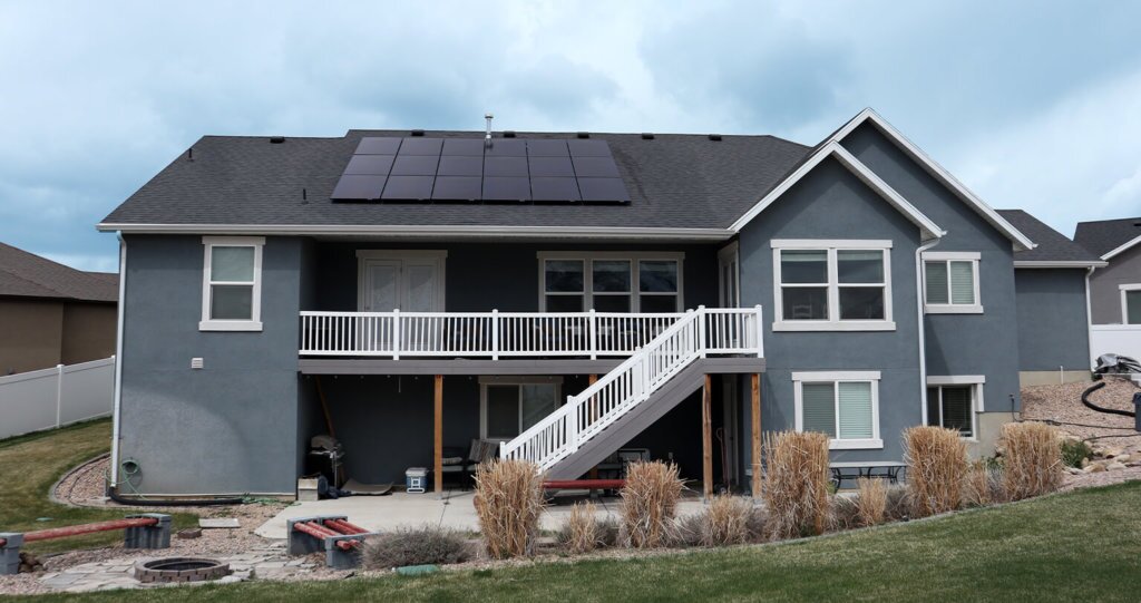 Back preview of two-story, grey-blue house with large solar panel system installed on roof
