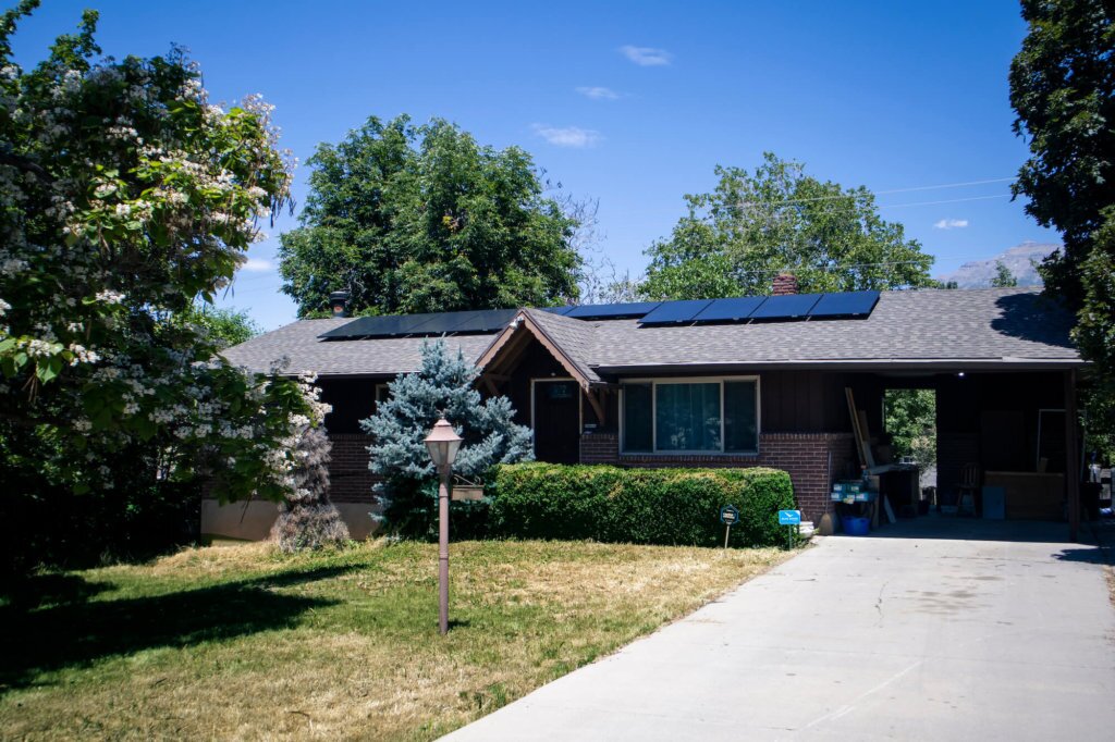 Single level house with brick accents and solar panels installed on front part of roof