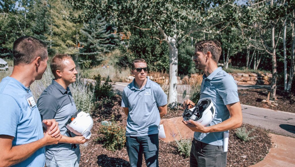 Four Blue Raven Solar executives meeting together on-site of an installation, holding hard hats