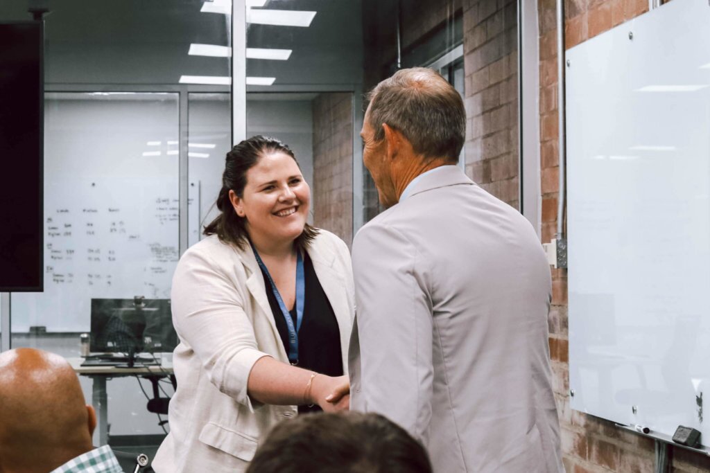 Blue Raven Solar Director, shaking hands with a Congressman in a conference room
