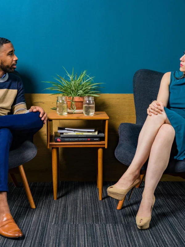 Two individuals, one male and one female sitting and looking at each other in deep conversation