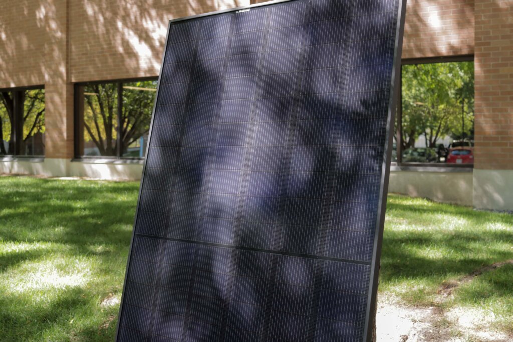 Free standing solar panel in front of red, brown brick building, Blue Raven Solar Corporate Office
