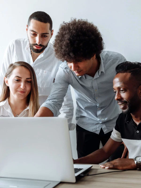 Three males and one female, gathered around a laptop - working in a group setting