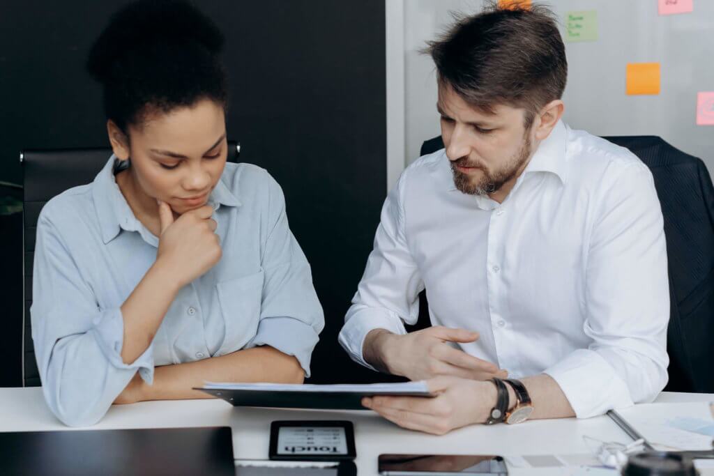 Two employees meeting together and discussing paperwork during a meeting