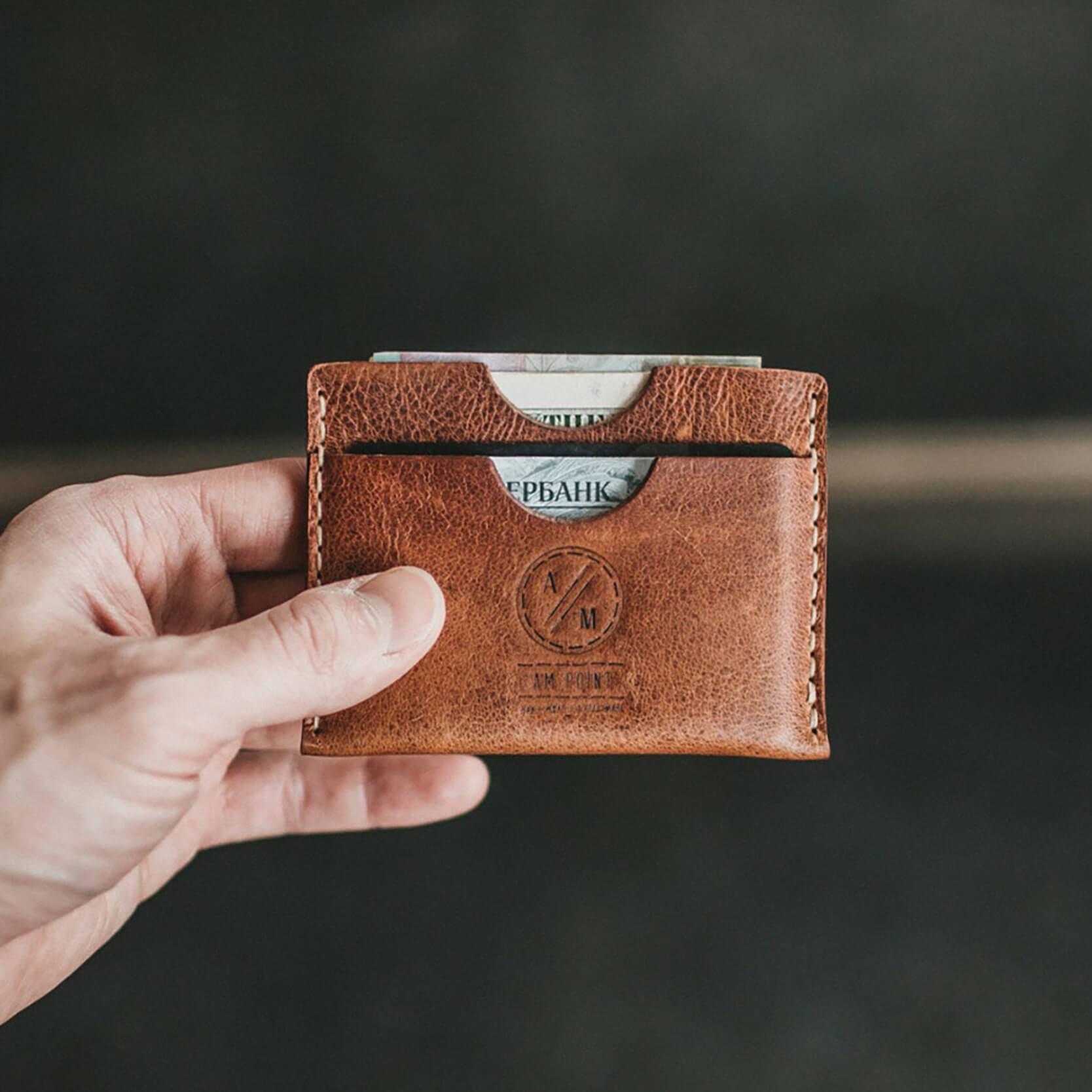 Male holding a brown leather wallet with cash and ID