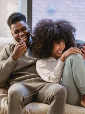 Happy couple, laughing and cuddling on the couch