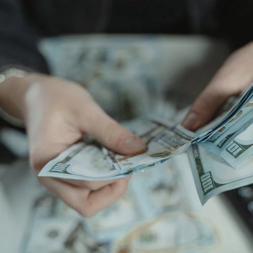 Hands holding and fanning out hundred dollar bills