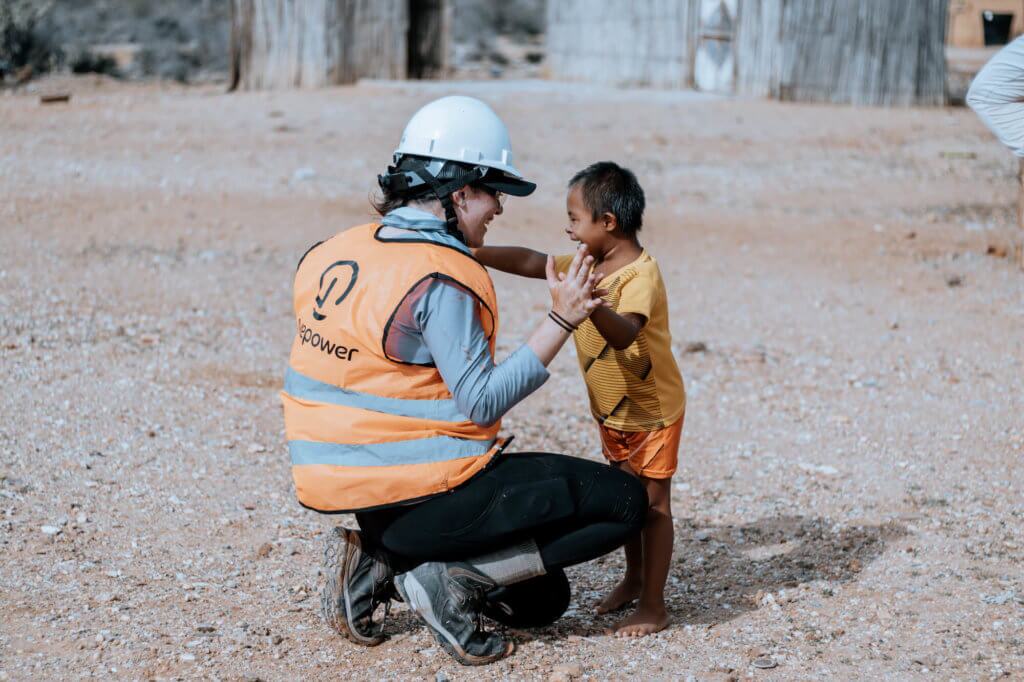 GivePartner with Little Boy GivePower in an orange vest with white hardhat, swatting down and holding hands with a small, young boy