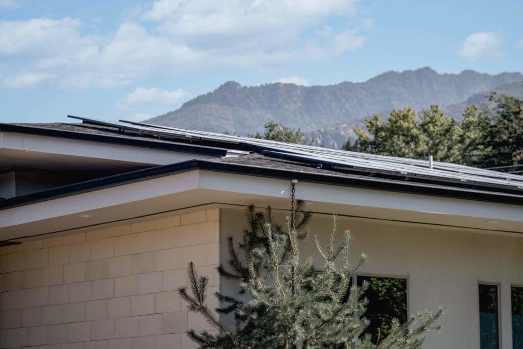 Sandy UT solar panel installation_roofline Up close view of roof line, featuring custom solar panel installation and mountains and blue sky in background