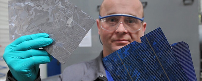 Bald, white, male with safety glasses and turquoise gloves holidng solar panel scraps