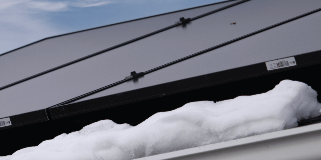 Are Solar Panels Waterproof-02 Solar panel array installed on roof with snow piles below and blue skies above