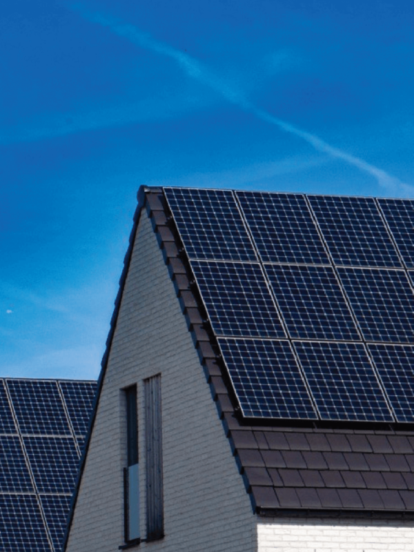 Houses, side-by-side with solar panel systems installed on the roof and blue skies in the background