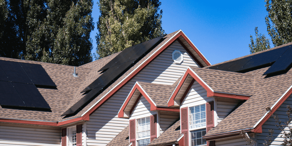 House with brown asphalt shingles, large solar panel installation on multiple pitches