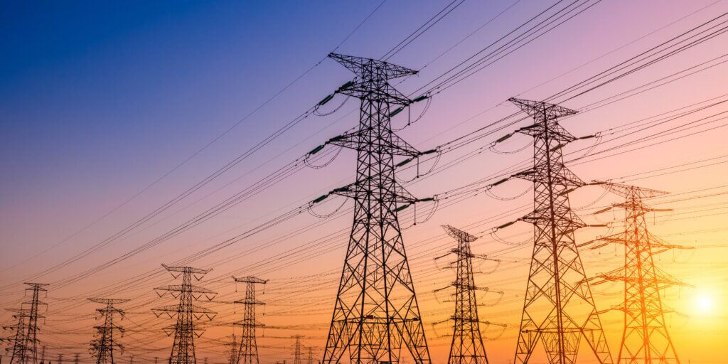 Multiple utility lines with vibrant sunset in the background - ranging from dark blue to yellow