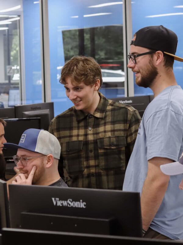 Group of Blue Raven Solar employees, standing and sitting around a computer monitor