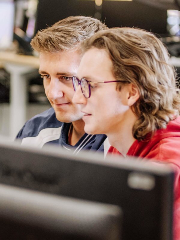Two, male Blue Raven Solar employees working together on a computer monitor