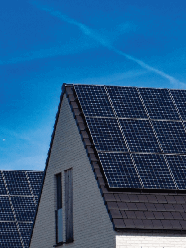 Houses, side-by-side with solar panel systems installed on the roof and blue skies in the background