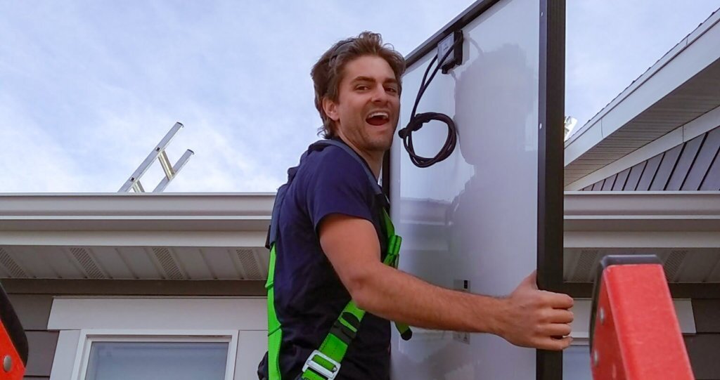 Blue Raven Solar's CEO, Ben Peterson holding a solar panel on a ladder in preparation for installation