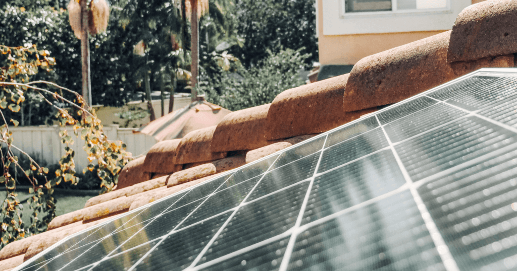 Solar panel on terracotta clay or ceramic roof with palm trees in the background