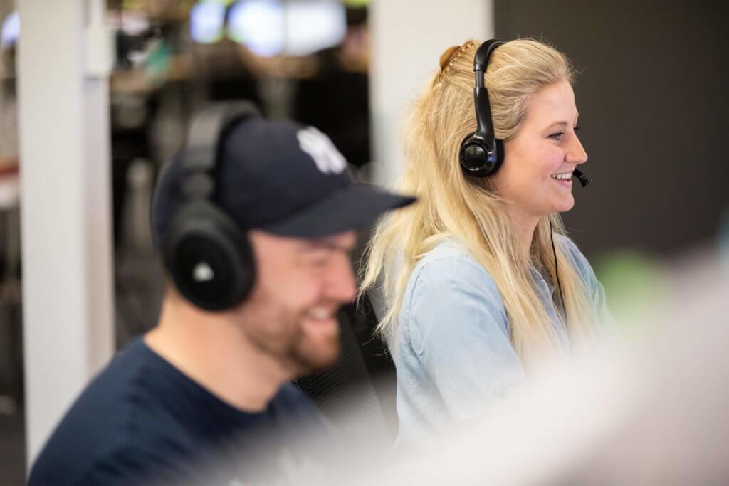 Two Blue Raven Solar support representatives with headphones looking at computer monitors