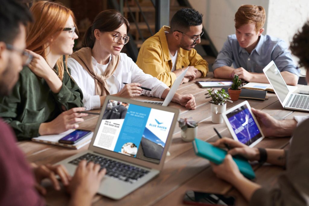 Large team meeting, in a conference room, where all team members are gathered around a table working independently