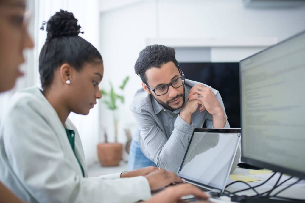 Three employees collabrating together, while two work on their computers