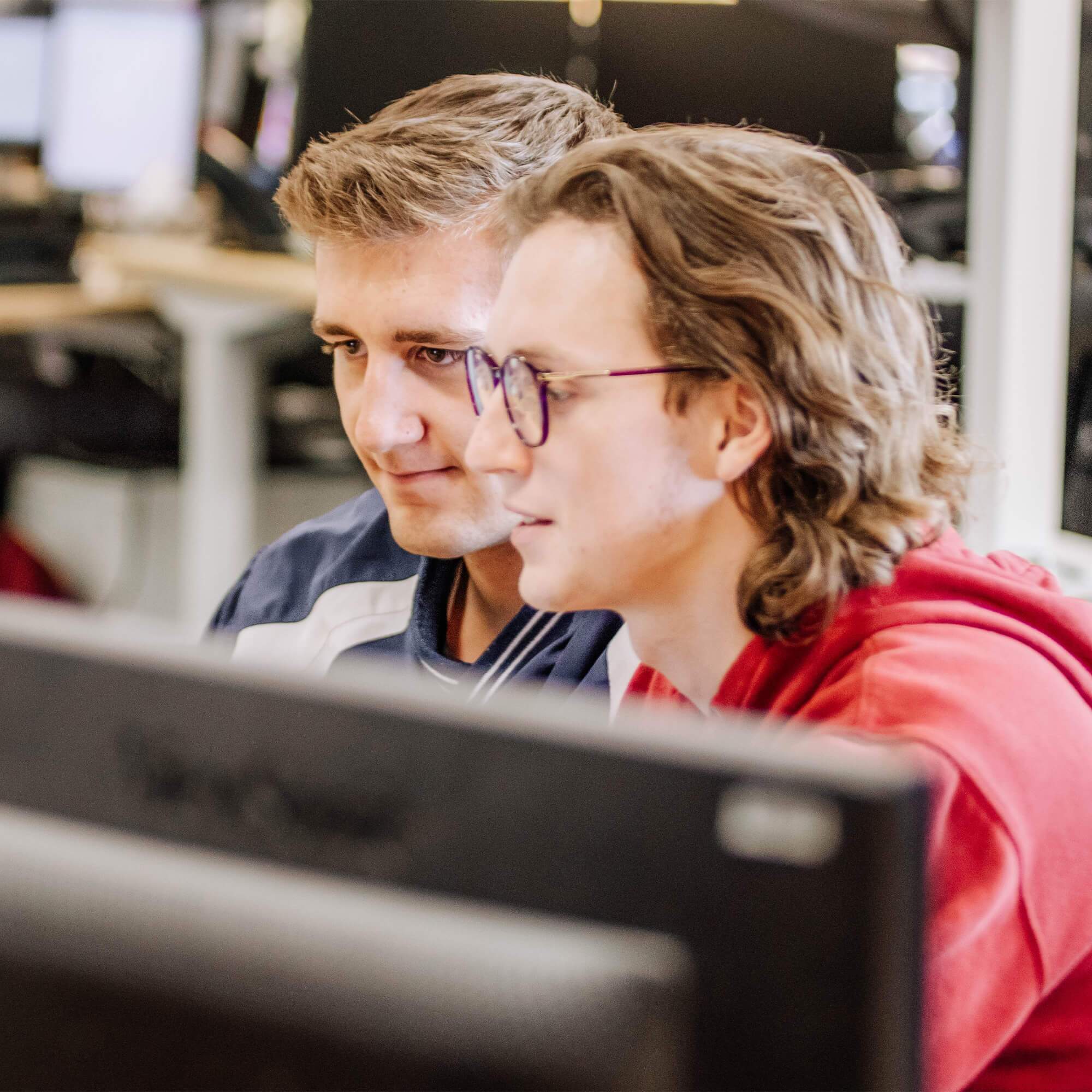 Two, male Blue Raven Solar employees working together on a computer monitor