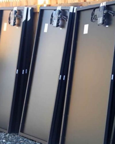 Solar Panels Aligned Back of solar panels, leaning against a wood fence in preparation for installation