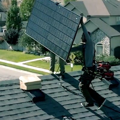 Solar-Installers-on-Roof Two solar installers, carrying solar panel on roof to get into position