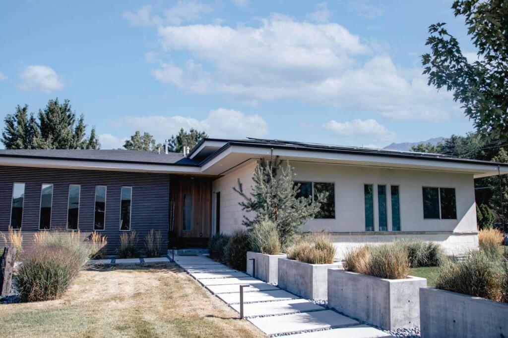 Modern, single-level house design from the front containing five small, rectangular windows and concrete planter boxes