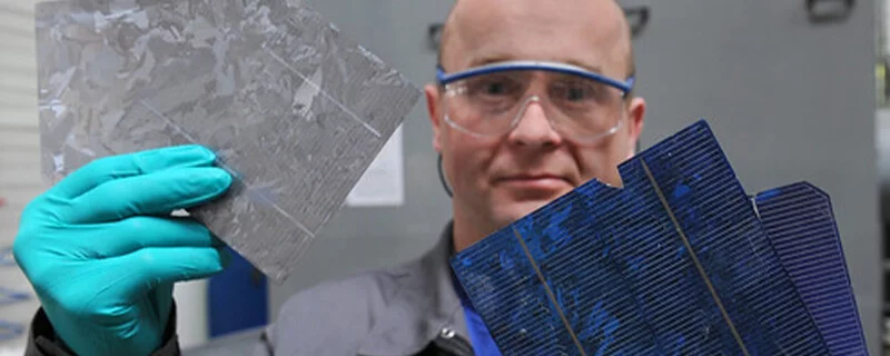 Solar-Recycling-Personnel Bald, white, male with safety glasses and turquoise gloves holidng solar panel scraps