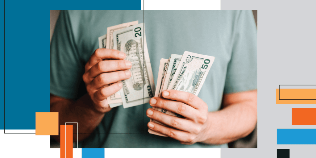 A male in a pale green shirt holding large amounts of cash in both hands