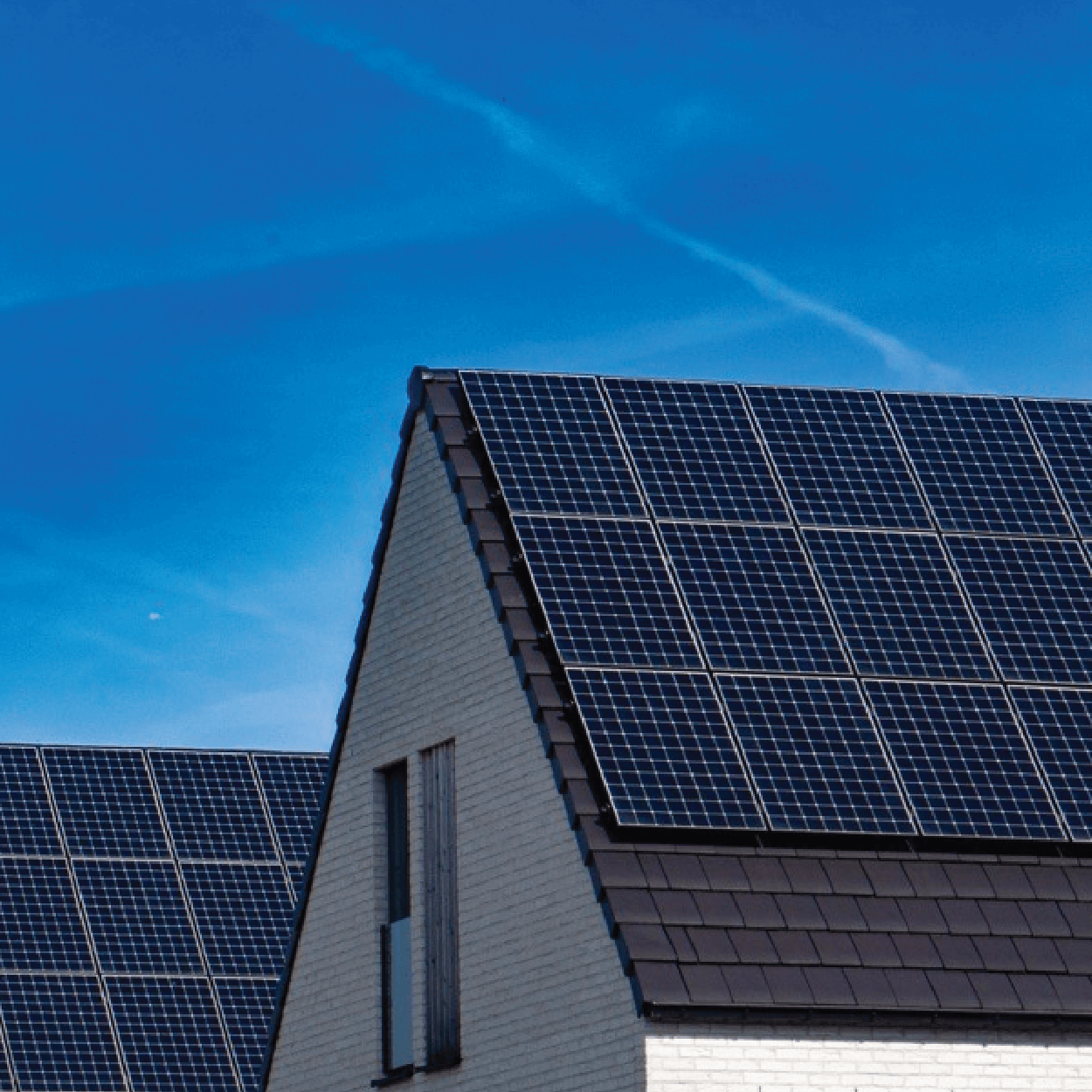 Houses, side-by-side with solar panel systems installed on the roof and blue skies in the background