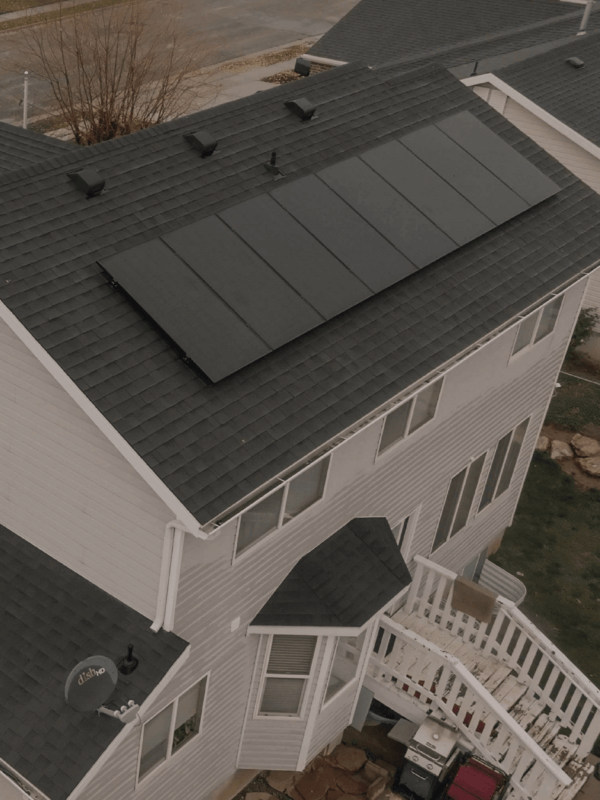 Aerial shot of a large two-story house with solar panels installed on different pitches